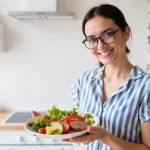 Young-Indian-woman-holding-a-plate-of-assorted-functional-foods,-symbolising-muscle-friendly-nutrition-with-ragi,-moringa,-turmeric,-dairy,-and-seeds