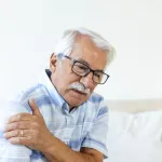 Elderly-man-holding-his-shoulder-in-discomfort,-symbolising-progressive-muscle-weakness-in-ageing-adults—supported-by-ImproSyn-and-Care-for-Muscles